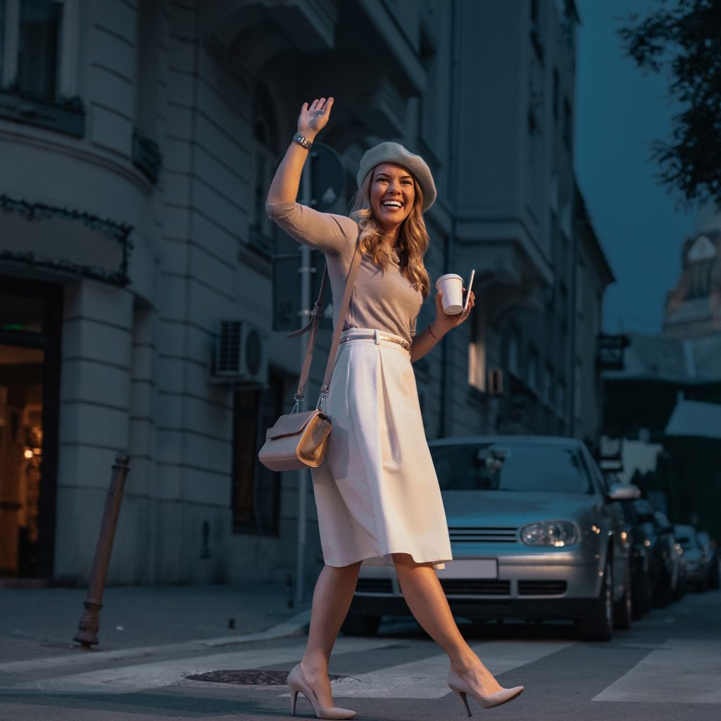 woman in a beret waving while crossing the street in Paris